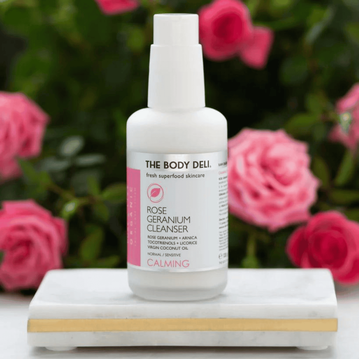 Body Deli Rose Cleanser surrounded by rosebush